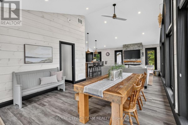 Open concept living room with vaulted ceiling, fireplace, and wood dining table - 2815 Golf Course Lane North Grenville