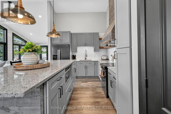 Gray cabinets, granite countertops, and island in a modern kitchen - 2815 Golf Course Lane North Grenville