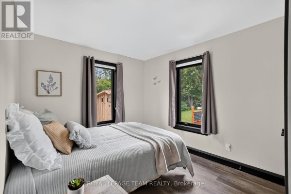Bedroom with quilt, pillows, wall art, and backyard view - 2815 Golf Course Lane North Grenville