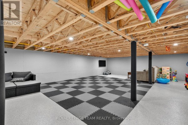 Finished basement with interlocking floors, sofa, TV, and toys - 2815 Golf Course Lane North Grenville