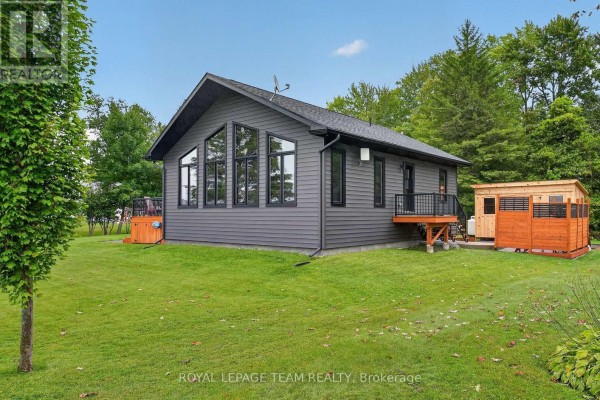 Modern grey house with large windows, deck, and outbuilding - 2815 Golf Course Lane North Grenville
