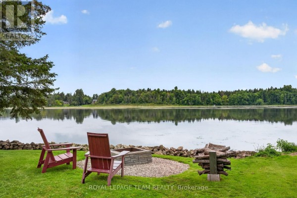 Lakefront yard with Adirondack chairs and fire pit - 2815 Golf Course Lane North Grenville