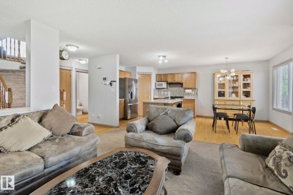 Open concept living space showing the living room, kitchen, and dining area with wood floors. - 2819 33 St Nw Nw, Edmonton
