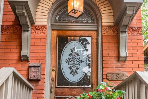 Close-up of the wooden front door with glass insert and ornate detailing. - 282 Hess Street S, Hamilton