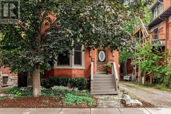 Full view of the brick house exterior from the street with mature trees. - 282 Hess Street S, Hamilton