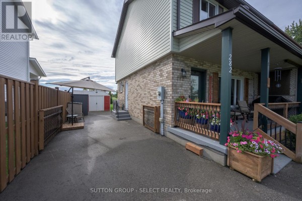 View of the driveway and side yard with a detached garage and wooden fence. - 282 Marsh Line, Dutton/dunwich