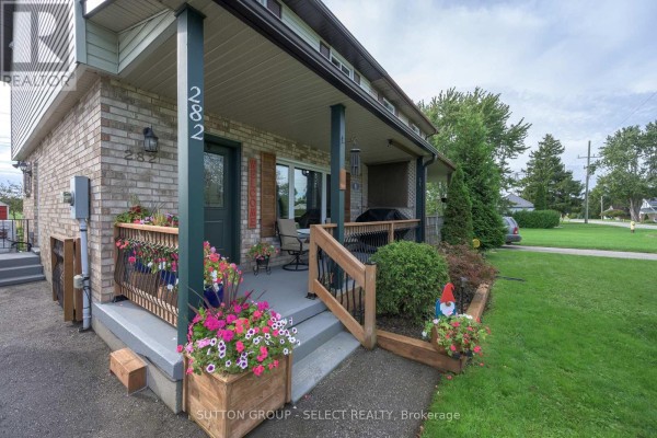 Covered front porch with wooden railings, chairs, and flower planters. - 282 Marsh Line, Dutton/dunwich