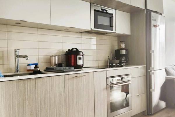 Modern kitchen with stainless steel appliances, light wood cabinets, and white subway tile backsplash. - 2821 - 585 Bloor Street E, Toronto