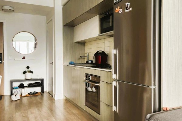 Apartment entryway with a round mirror, shoe rack, and adjacent modern kitchen. - 2821 - 585 Bloor Street E, Toronto
