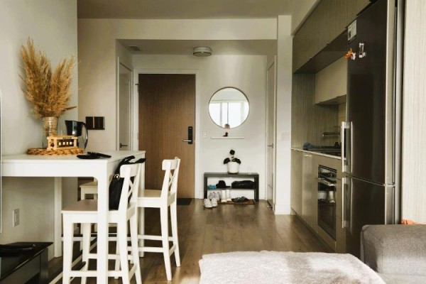 Dining area with white table and stools, leading to entryway and kitchen. - 2821 - 585 Bloor Street E, Toronto