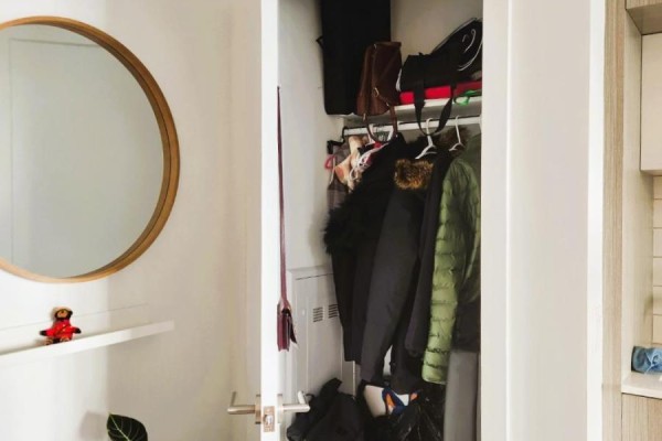 Open closet with hanging coats and bags, next to a round mirror. - 2821 - 585 Bloor Street E, Toronto