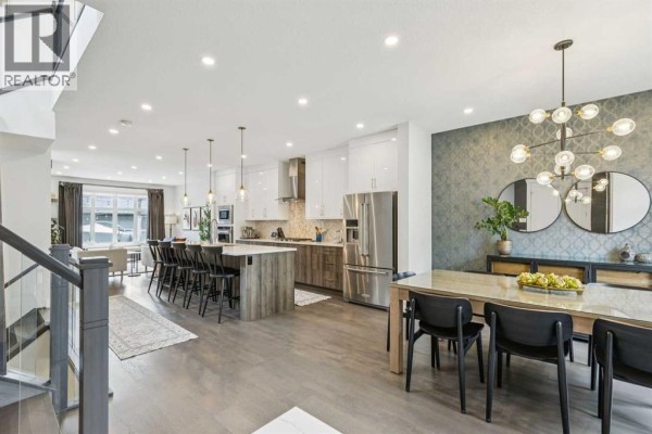 Open concept living, dining, and kitchen area with hardwood floors and island. - 2826 40 Street Sw, Calgary