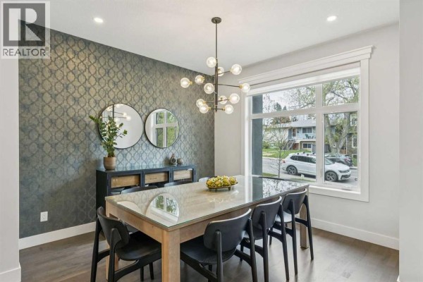Dining area with a large window, patterned wallpaper, and modern chandelier. - 2826 40 Street Sw, Calgary