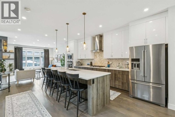 Spacious kitchen with white cabinets, stainless steel appliances, and large island with seating. - 2826 40 Street Sw, Calgary