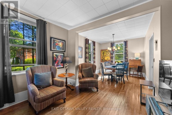 Living area with two armchairs, side table, and dining area view. - 283 & 285 William Street, Pembroke