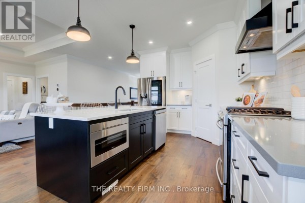 Open concept kitchen and living area with white cabinets, island, and a glimpse of living room furniture. - 283 Elizabeth Street, Southwest Middlesex