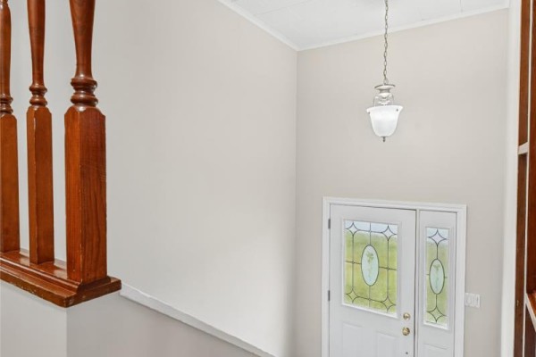 View from above of the entrance foyer with double front doors, a hanging light fixture, and wooden railings. - 283 Fowlers Road, Conception Bay South