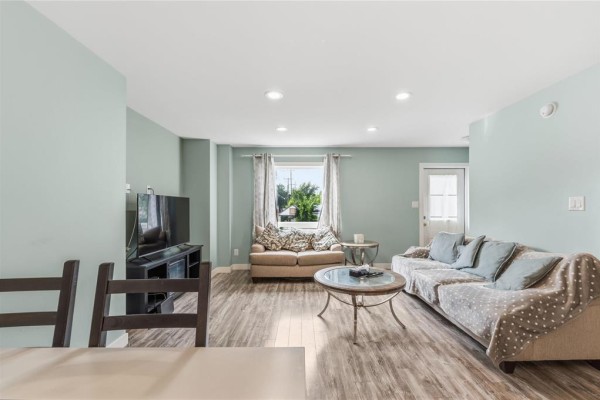 Living room with light blue walls, two couches, a coffee table, and a television. - 283 Mckenzie Street, Winnipeg