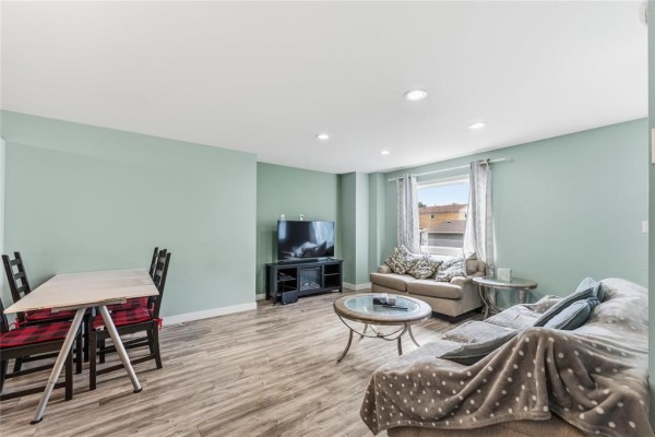 Living room with light blue walls, dining table, couches, coffee table, and television. - 283 Mckenzie Street, Winnipeg
