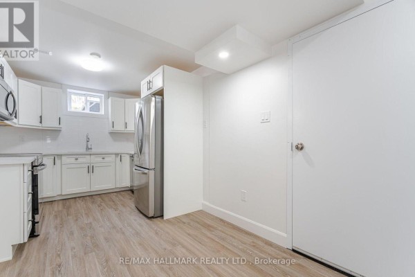 White kitchen with stainless steel refrigerator, sink, and oven in a spacious room. - 283 Porter - Lower Level Street, Oshawa