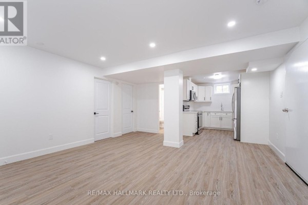 Open concept living area connected to a kitchen with white cabinets and light wood floors. - 283 Porter - Lower Level Street, Oshawa