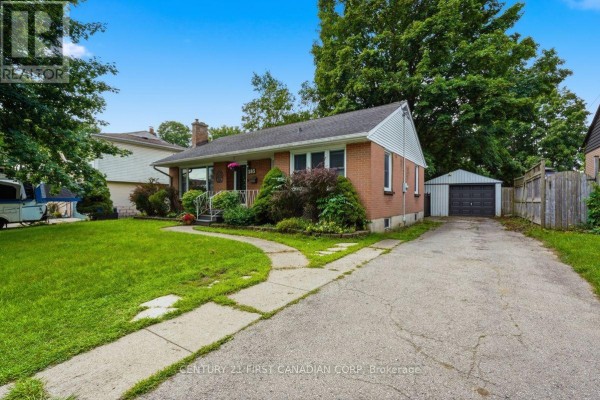 Side view of a brick bungalow with a driveway leading to a detached garage. - 283 Spruce Street, London East
