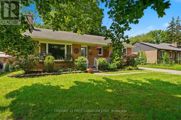 Front exterior of a brick bungalow with a manicured lawn and mature trees. - 283 Spruce Street, London East