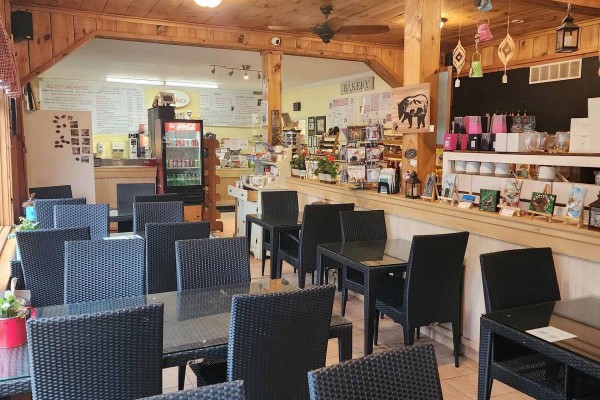 Dining area inside Erika's Bakery with black tables and chairs and wood-paneled walls. - 2832 60 Highway, Lake Of Bays