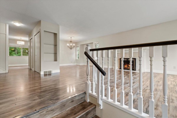 Interior view of a home showing a staircase, hallway, living room with fireplace, and dining area. - 2833 Gardner Place, Abbotsford