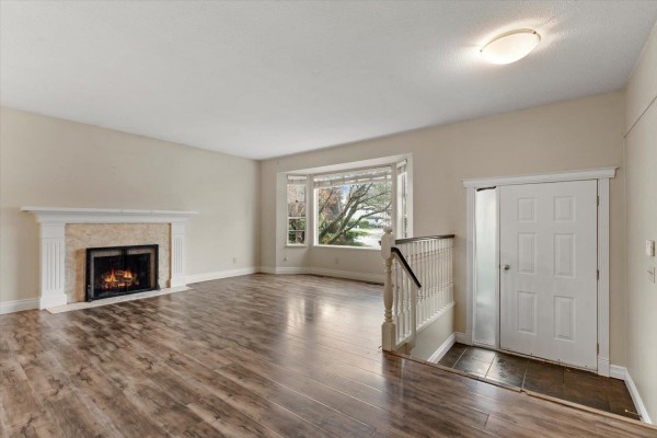 Living room with a marble fireplace, large bay window, and white double doors leading outside. - 2833 Gardner Place, Abbotsford