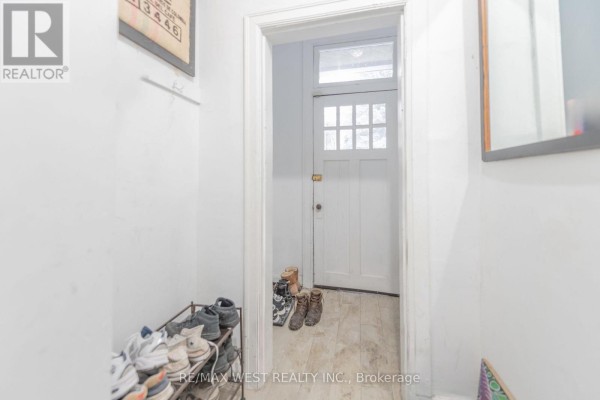 Interior view of a narrow entryway with a shoe rack and a white door. - 284 Lisgar Street, Toronto