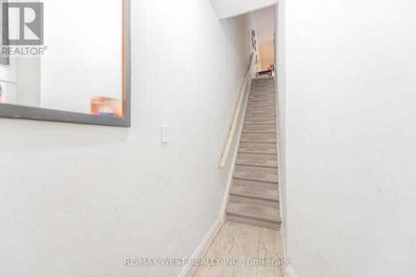 Narrow staircase with carpeted steps and a wooden handrail against a white wall. - 284 Lisgar Street, Toronto