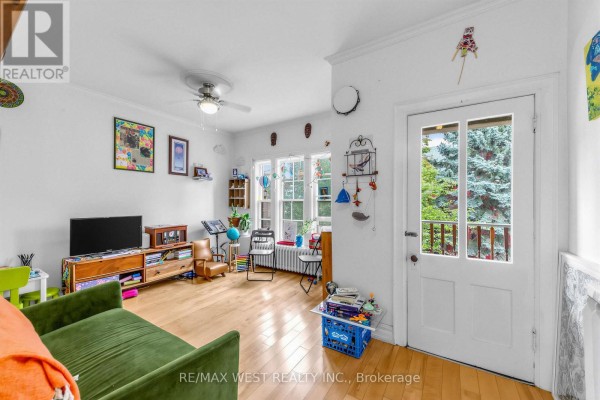 Living room with a green sofa, television, wooden furniture, and large windows. - 284 Lisgar Street, Toronto