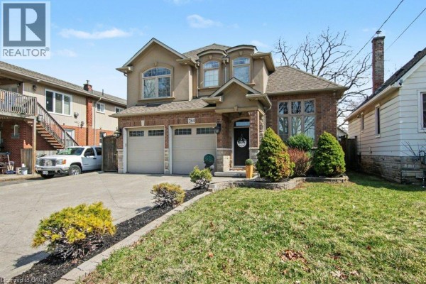 Front view of a two-story house with a concrete driveway, brick detailing, and landscaping. - 284 Normanhurst Avenue, Hamilton