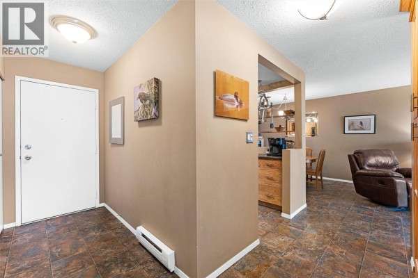 Building entrance with brick facade, covered walkway, and paved walkway. - 284 Yortkton Avenue Unit# 205, Penticton