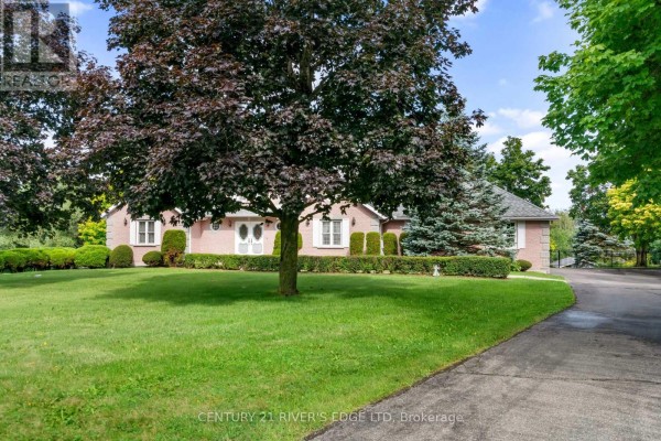 View of the brick house entrance with a large tree in the foreground and driveway. - 2840 2nd Concession Road, Elizabethtown Kitley
