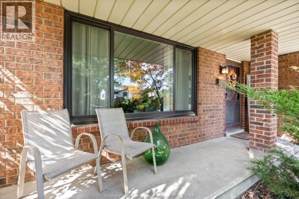 Dining area with a table covered in a floral tablecloth, white upholstered chairs, and hardwood floors. - 2841 Garvey Crescent, Windsor