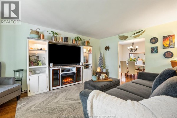 Living room with a television, electric fireplace, built-in shelving, and a view into the dining room. - 2841 Garvey Crescent, Windsor