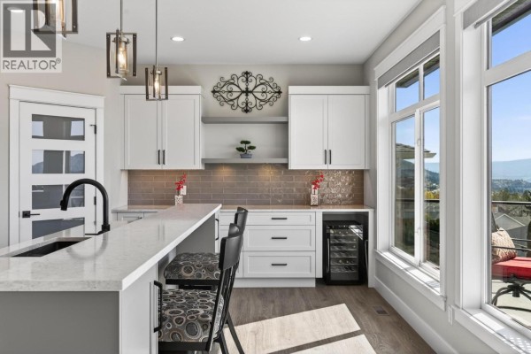 Kitchen bar area with white cabinets, wine fridge, and large windows with a valley view. - 2847 Copper Ridge Drive, West Kelowna