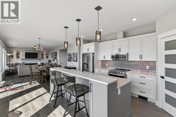 Open-concept kitchen and living room with a fireplace and dining area, viewed from the kitchen island. - 2847 Copper Ridge Drive, West Kelowna