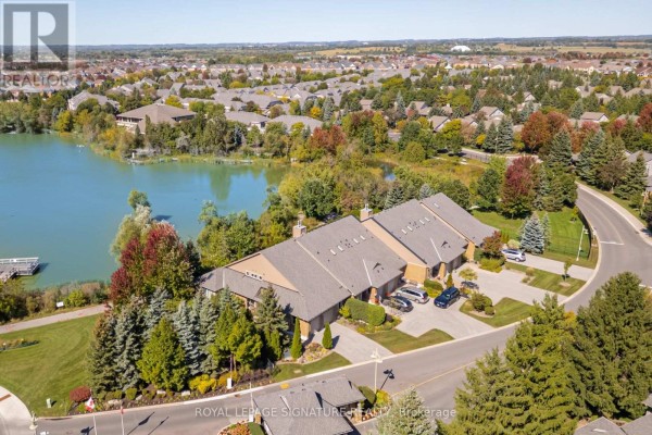 Aerial view of townhouses on a street beside a lake with surrounding trees and houses. - 285 - 8 Lakeside Vista Way, Markham