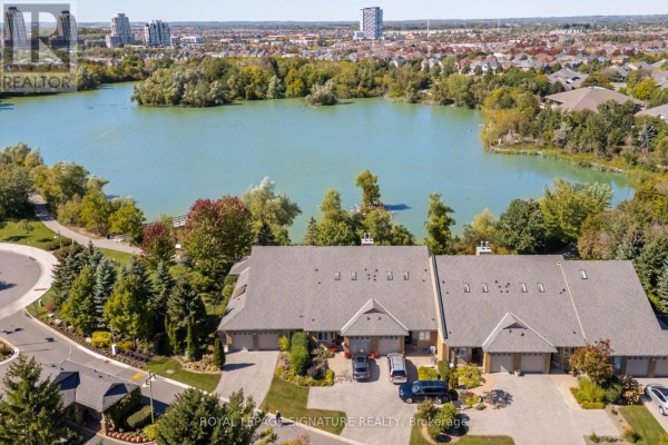 Aerial view of townhouses with a lake and trees in the foreground and cityscape in the background. - 285 - 8 Lakeside Vista Way, Markham