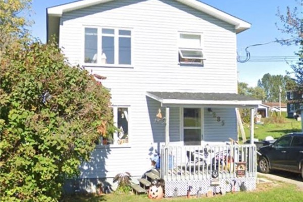 Front view of the home with a porch and landscaping. - 285 Church, Bathurst