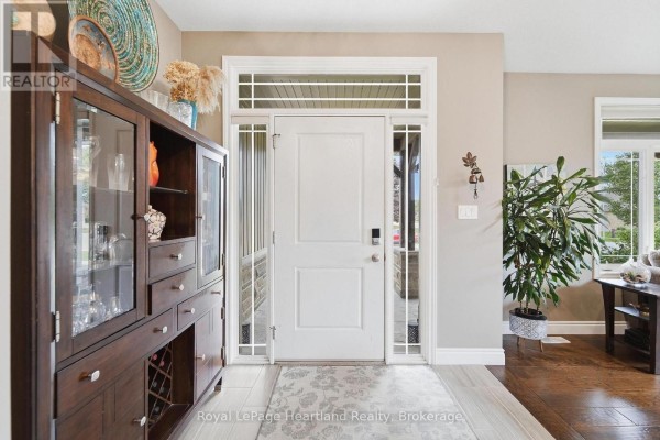 Interior view of a beige front hall with a white door, sidelights, and a dark wood cabinet. - 285 Darling Boulevard, South Huron