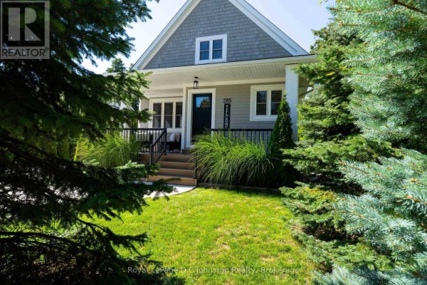 View of the front of the house framed by lush green evergreen trees. - 285 Huron Street S, Saugeen Shores
