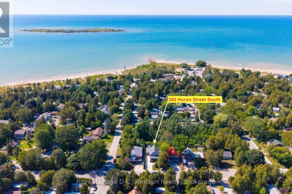 Aerial view of 285 Huron Street South in a wooded neighbourhood near a large body of water. - 285 Huron Street S, Saugeen Shores