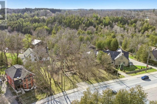 Aerial view of undeveloped lot with surrounding houses and wooded hills, property at 285 Main Street S, Guelph/eramosa. - 285 Main Street S, Guelph/eramosa