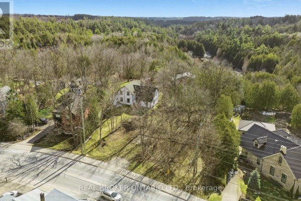 Aerial view of undeveloped lot with trees, houses, and wooded valley, property at 285 Main Street S, Guelph/eramosa. - 285 Main Street S, Guelph/eramosa