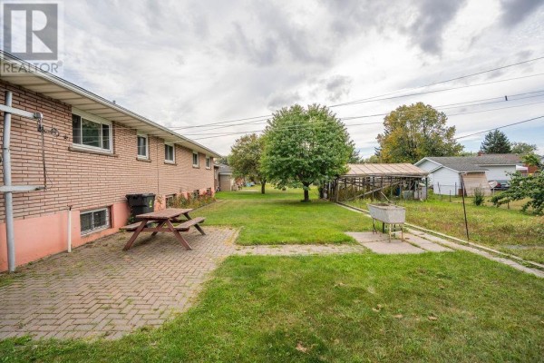 Another backyard view showcasing a picnic table, outdoor sink, and a grassy area. - 285 Spadina Ave, Sault Ste  Marie