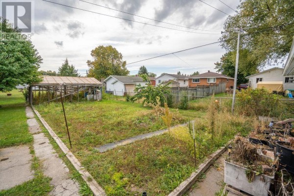 Overhead view of the backyard showing a greenhouse structure and surrounding houses. - 285 Spadina Ave, Sault Ste  Marie